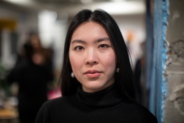 A portrait of an Asian woman wearing a black, turtle-neck shirt.