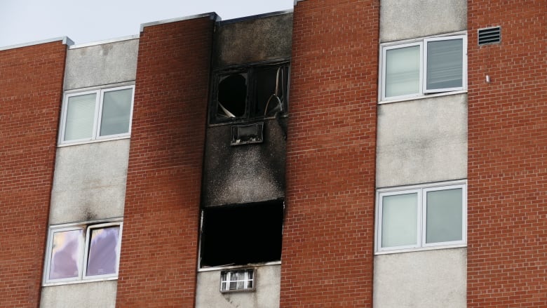 An apartment building with smoke damage outside a window.