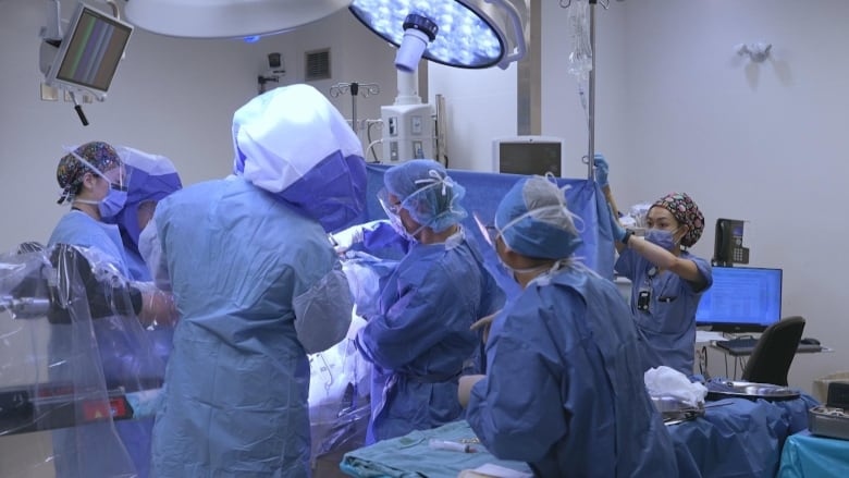 An operating room team of doctors and nurses during a hip replacement surgery.