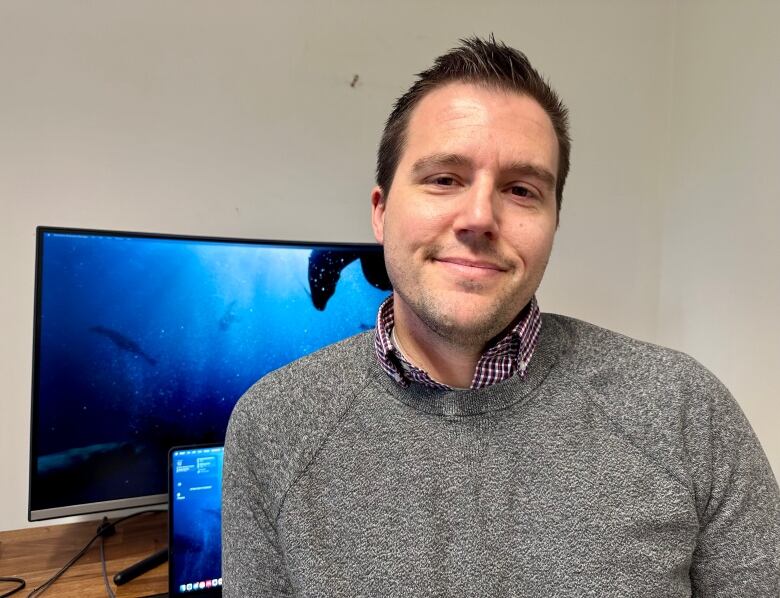 A man stands in front of a computer.