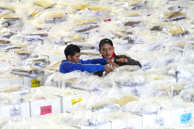 Two people completely surrounded by boxes. 