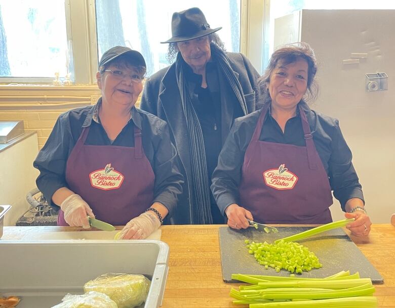 Chester Knight's Bannock Bistro head Chef Brenda Knight, and her sister Karen Pahtayken chop up vegetables while cree musician 