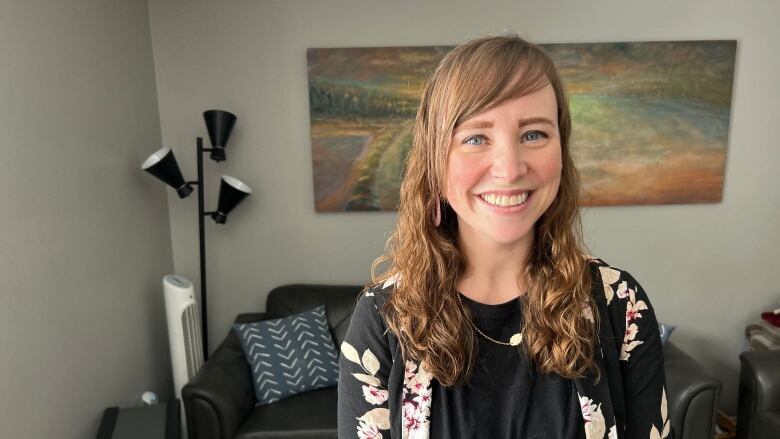 Young woman with long brown hair smiles in the living room at Blooming House. 