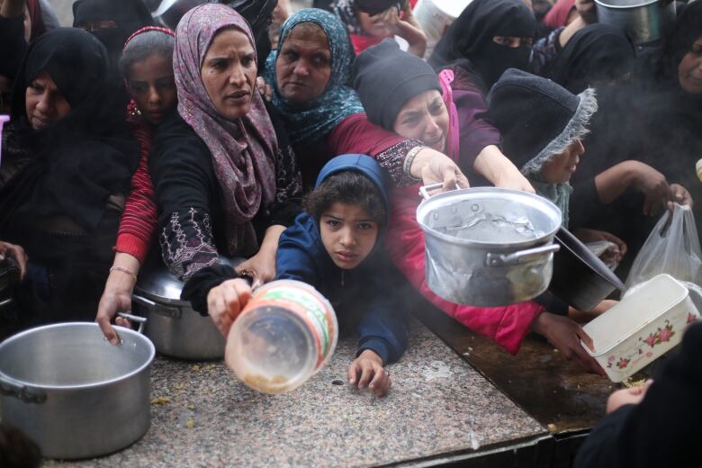 Palestinians crowd around a food aid distribution point.