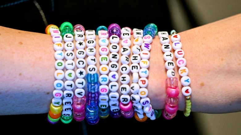 A person displays an arm full of colourful friendship bracelets, made of plastic beads.