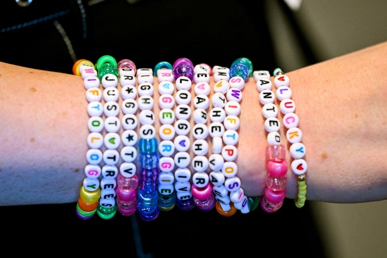 A person displays an arm full of colourful friendship bracelets, made of plastic beads.