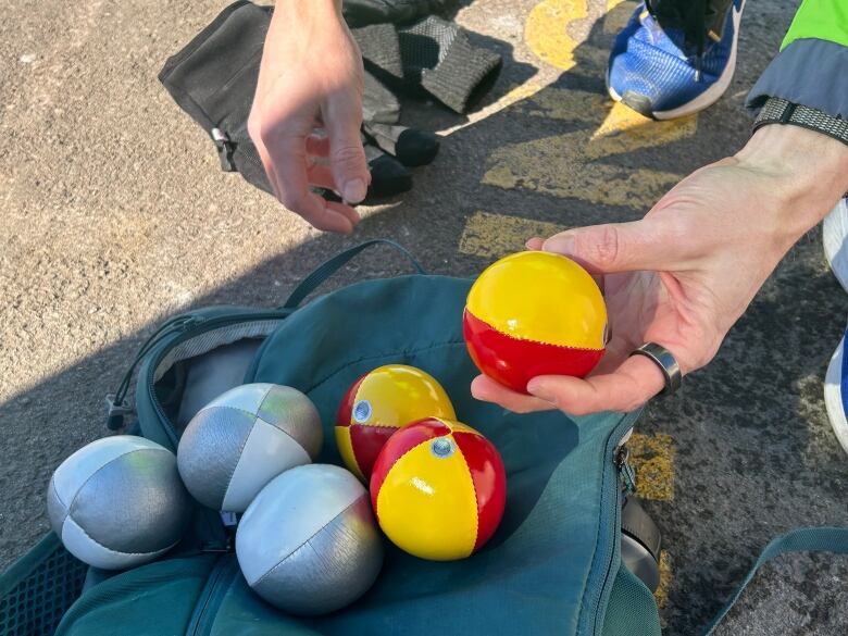 Six striped juggling balls, three are red and yellow and the other three are white and silver.