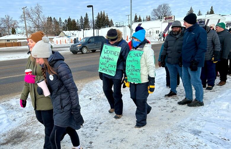 Teachers hold signs on the picket line in North Battleford. One says, 