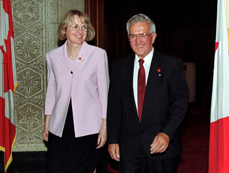 A man and a woman walk while smiling.