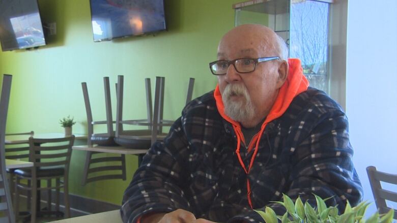 A man sits in a chair in a restaurant.