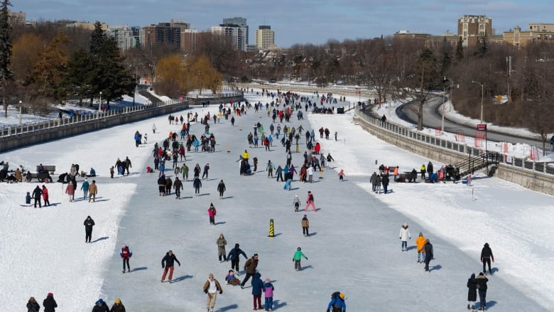 Crowd of people skate on a long, frozen river