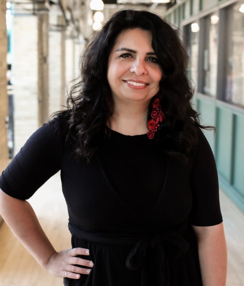 A woman poses for a portrait standing with her hand on her waist.