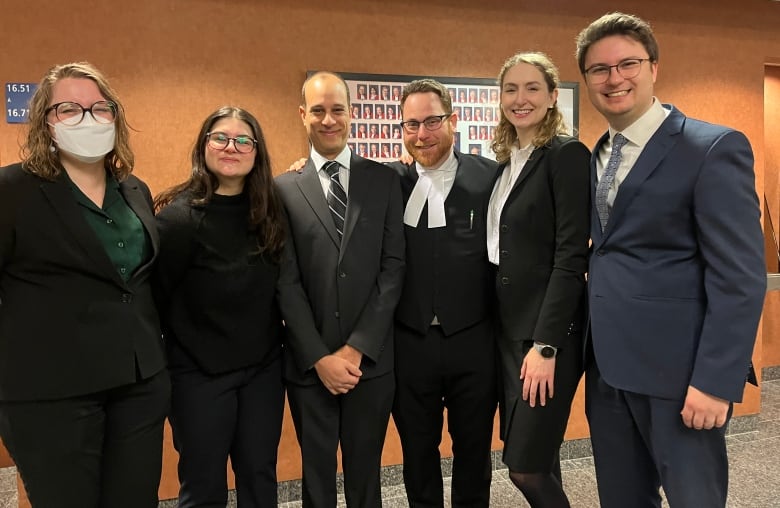 A group of lawyers stand in a courthouse hallway.