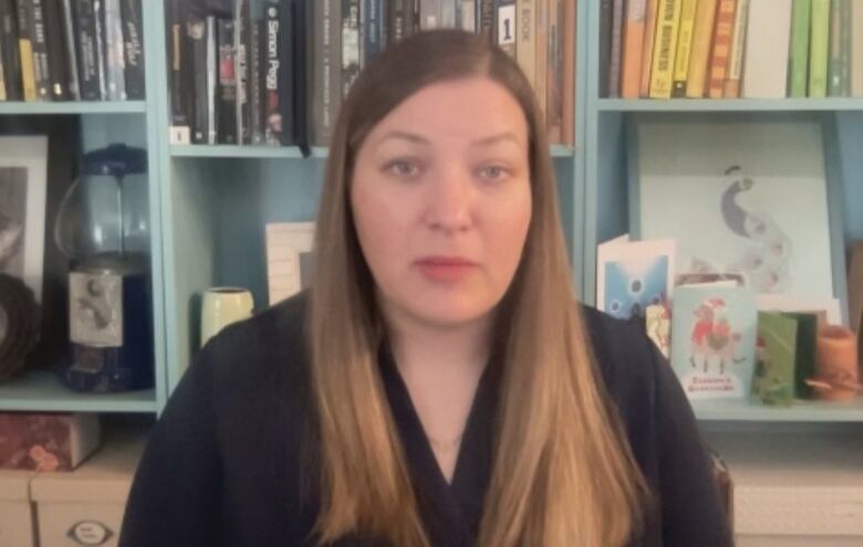 A woman in front of a bookcase.