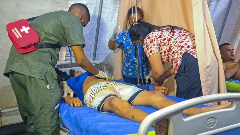 Two paramedics tend to a patient on a stretcher.