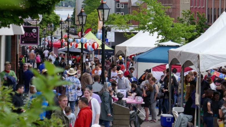 People gather at a street festival in downtown Charlottetown, with tents along the street.