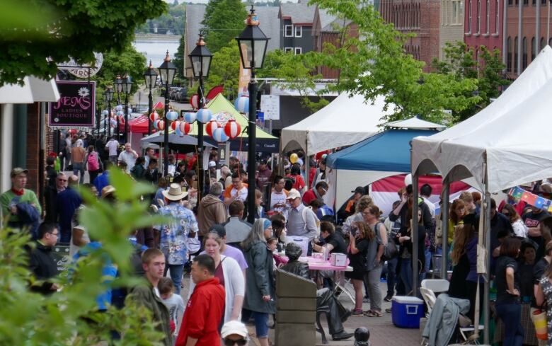 People gather at a street festival in downtown Charlottetown, with tents along the street.