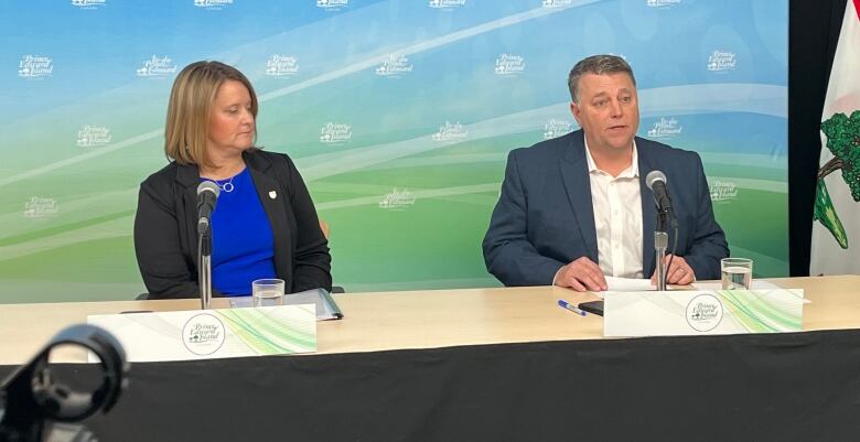 A woman and man sit at a table during a news conference. 