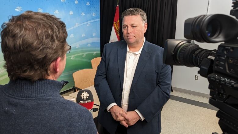 Premier Dennis King listens to a reporter's question in a legislature meeting room. 