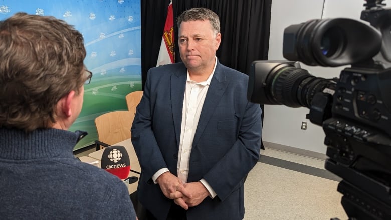 Premier Dennis King listens to a reporter's question in a legislature meeting room. 