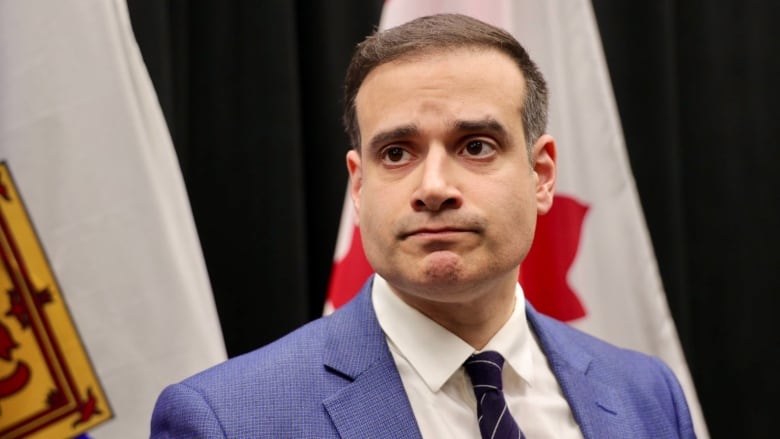 A man in a suite and tie listens to questions.