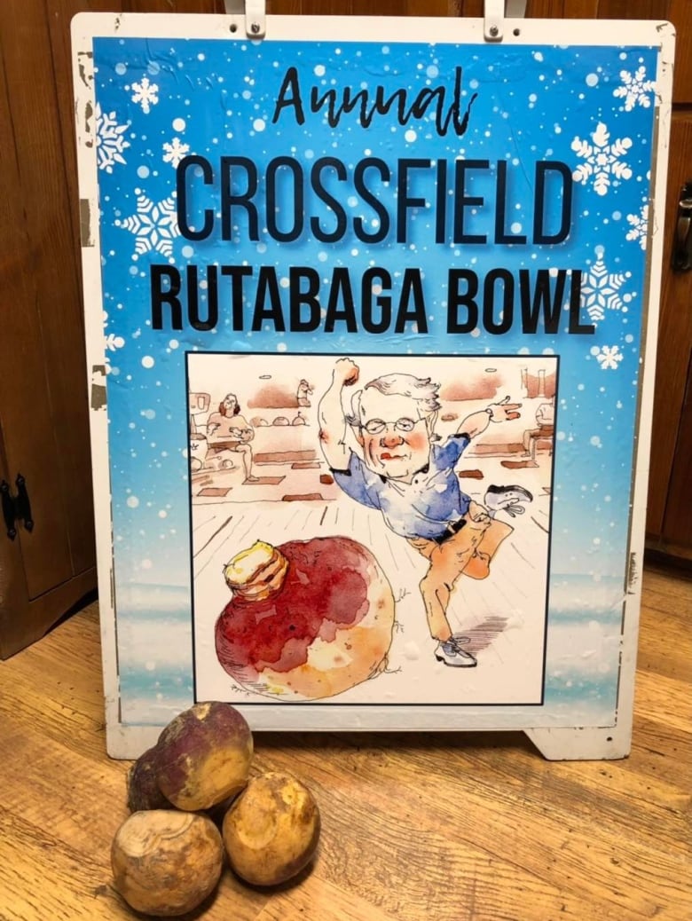 A colorful board with an illustration of a person bowling with rutabagas on a wooden floor. There are a few rutabagas visible next to the board.