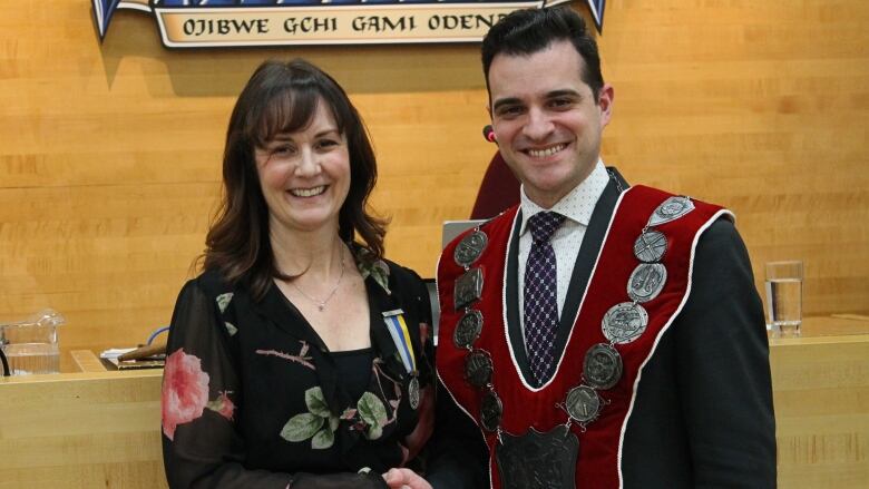 A smiling woman shaking a man's hand as they pose for a photo.