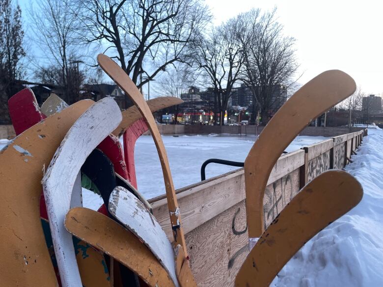 Empty outdoor skating rink at McNabb Park on Bronson Avenue, with hockey sticks in the foreground. 