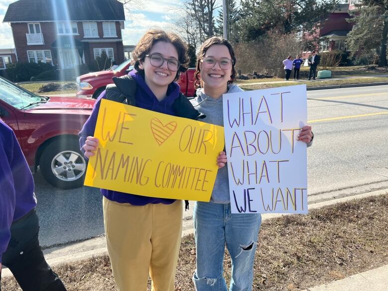 Two students holding signs, one saying 