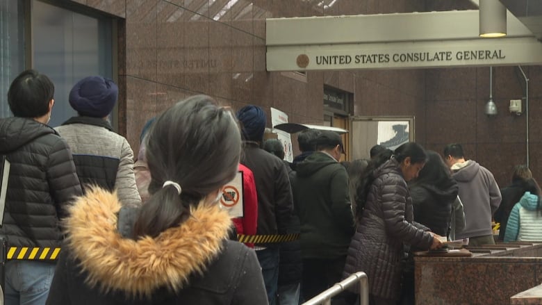 People line up to a building marked 