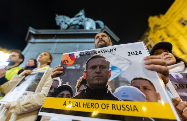 A man holds a placard in a public square.