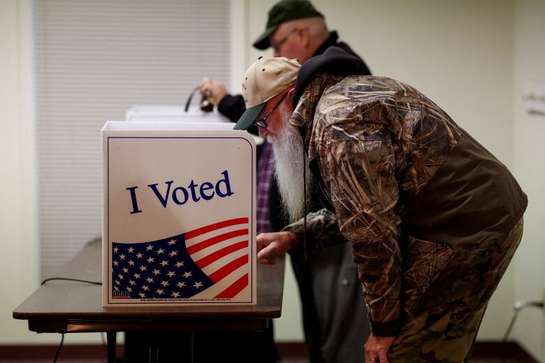 A voter bends over to cast a ballot at a voting station.