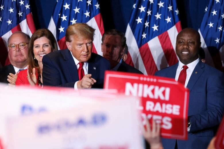 Trump points to crowd. One person holds a sign saying, 'Haley will raise your taxes'