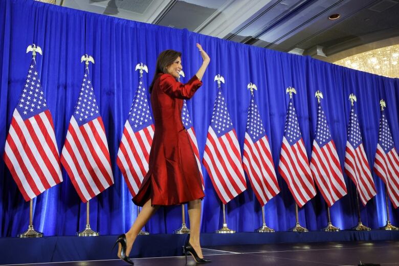 Haley waves on stage, with US flags behind her