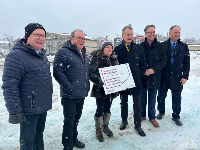 Six people standing on snow in a line. 