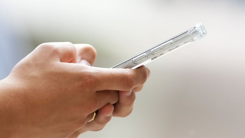 Photo showing a pair of hands using a cell phone.