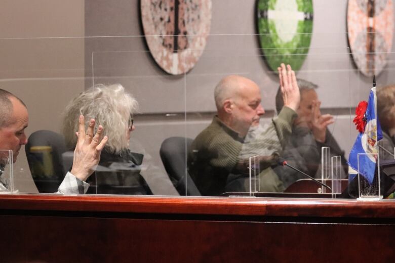 Several people behind a large desk with their hands raised.