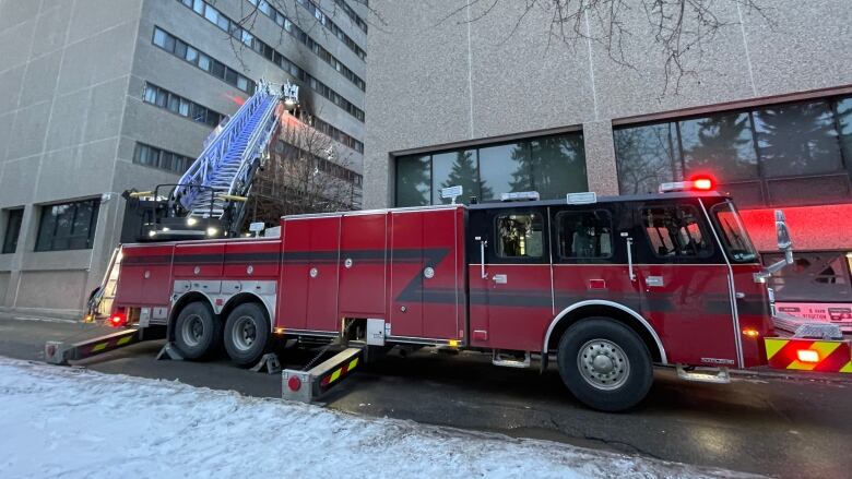 A fire truck with a ladder extended to an apartment building.