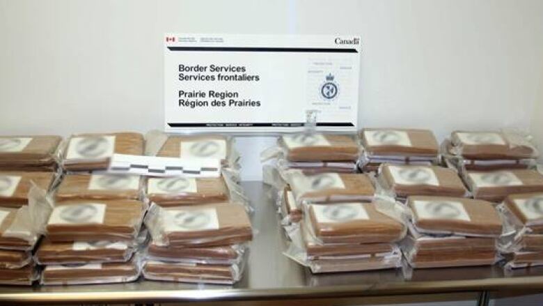 Stacks of brown packages believed to contain cocaine are piled on a table.