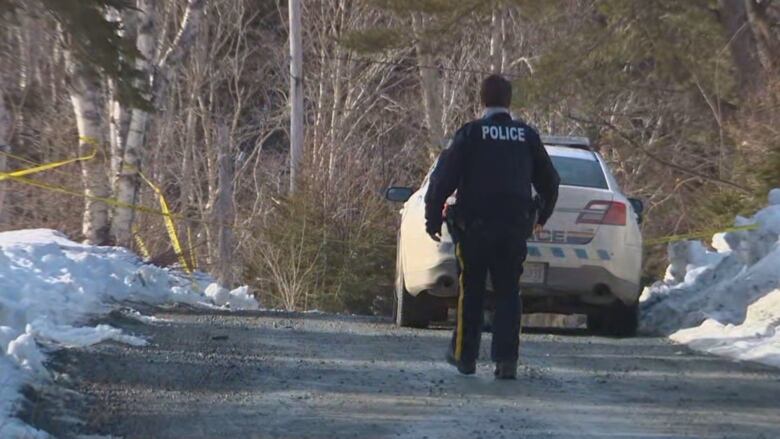 A police officer walks toward a home in Ruth Falls, N.S., on Tuesday, Feb. 27, 2024.