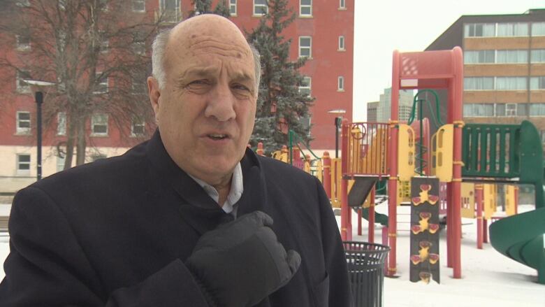 A man is pictured speaking front of a park playground.