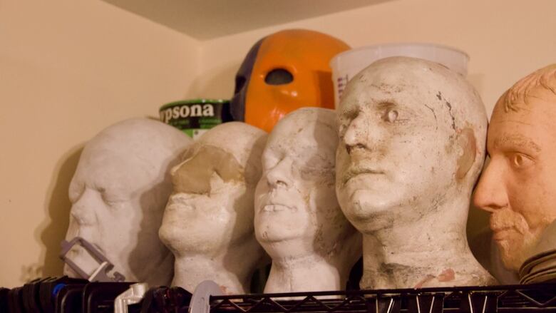 A row of model heads on top of a shelf.