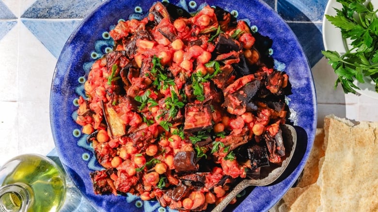 Overhead shot of Lebanese moussaka on a bright blue plate, on a blue and white tiled surface.  