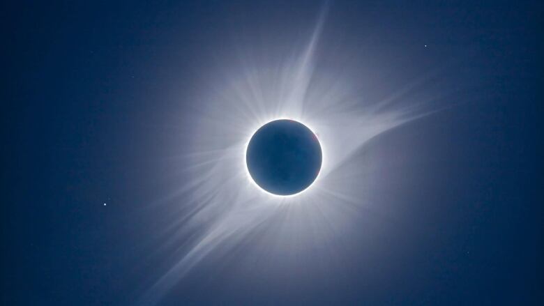 White streamers emanate from a black disk.