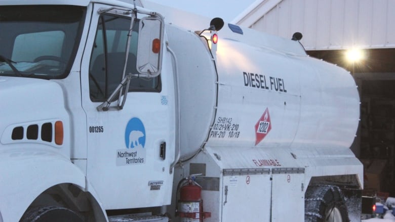 A diesel fuel truck in front of a garage in the winter.