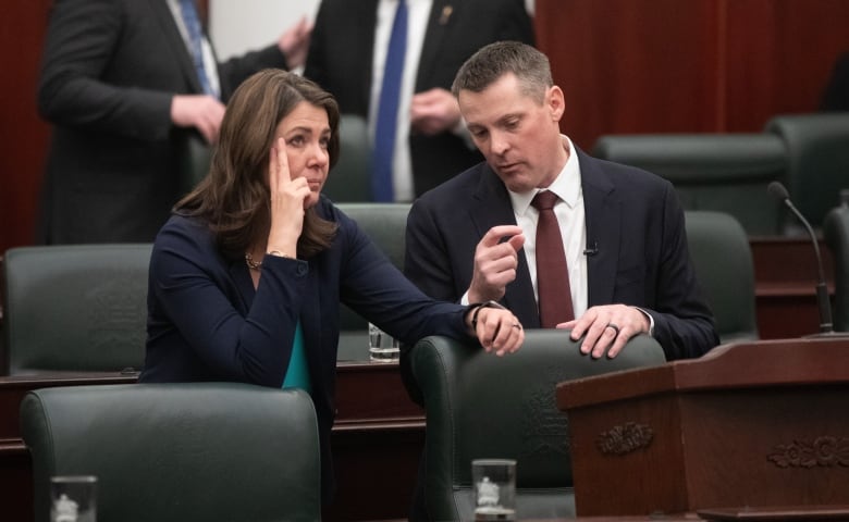 a woman and man talk while sitting at parliamentary benches