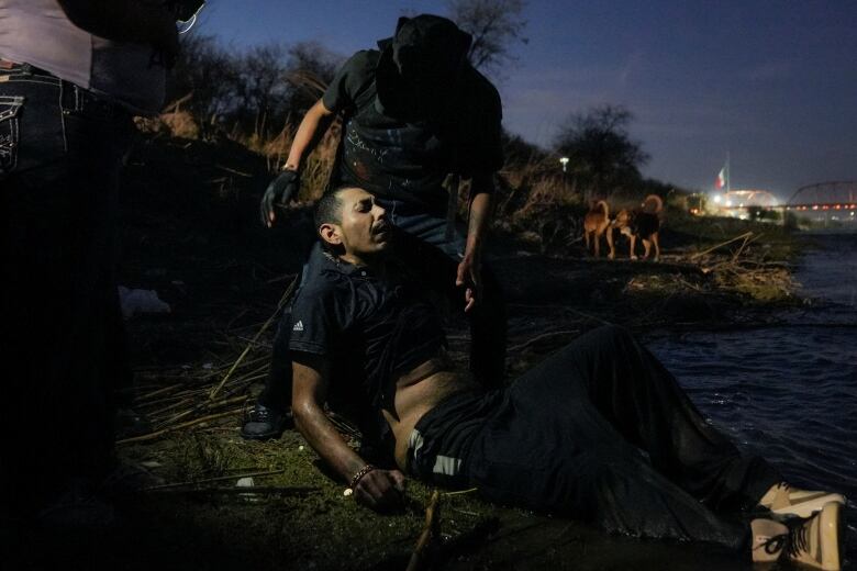 Man passed out, with other man propping him up