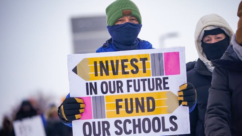 A person holds a sign that says 