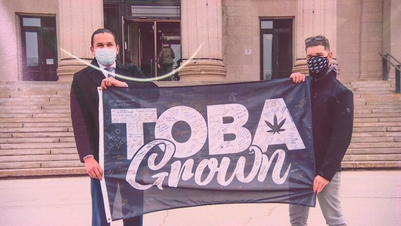 Two men holding a flag that says 'TobaGrown'