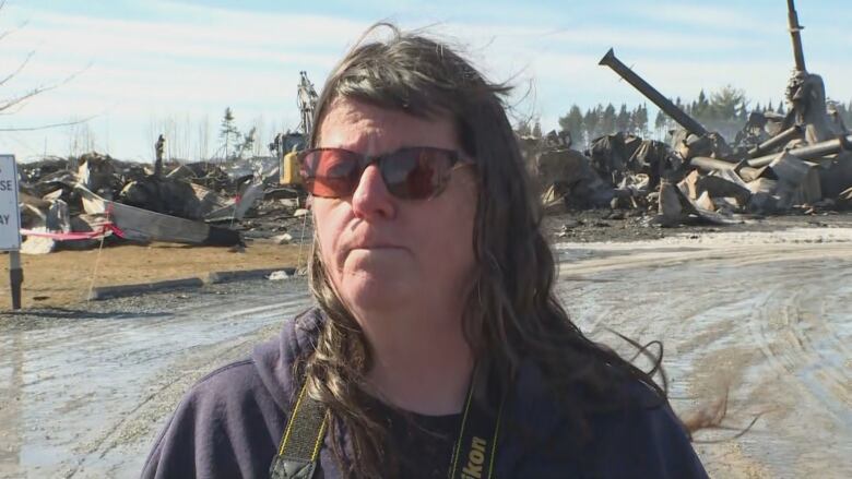 Tammy McLean stands in front of debris